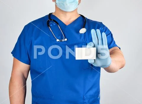 Doctor in sterile latex gloves and blue uniform holds a blank white business Stock Photos