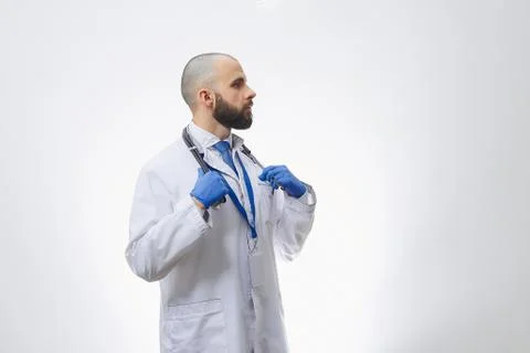 A doctor with a stethoscope in disposable gloves preparing to examine a patie Stock Photos