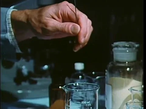 Doctor stirring solution in measuring glass in lab, 1970s 動画素材 64629940