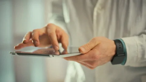 Doctor studies a panoramic x-ray on a digital tablet pinching to zoom and sc Stock Footage 333501183