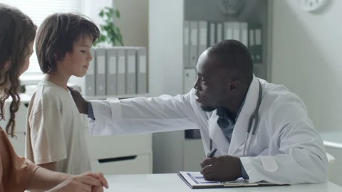 Doctor Supporting Young Boy during Pediatric Consultation in Medical Office Stock Footage 313810144