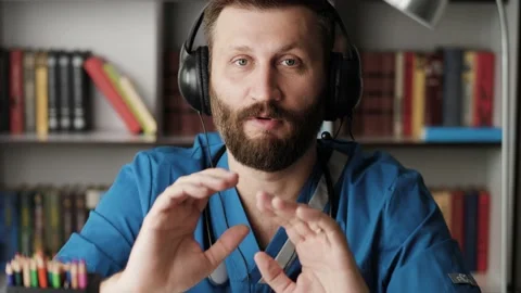 Doctor surgeon talking to camera. Attractive bearded doctor surgeon holds mock Stock Footage