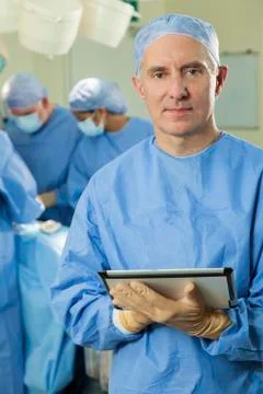 Doctor surgeon using tablet computer &amp; medical team Stock Photos