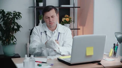 The doctor at the table puts on disposable gloves. Stock Footage 145614629
