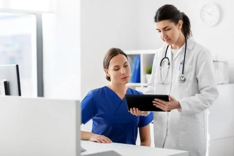 Doctor with tablet computer and nurse at hospital Stock Photos