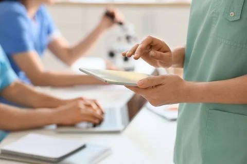 Doctor with tablet computer working in clinic, closeup 写真素材