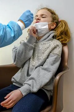 Doctor tacking a coronavirus test to an elementary age girl's nose with a med Stock-Fotos