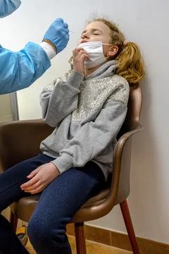 Doctor tacking a coronavirus test to an elementary age girl's nose with a med Stock Photos