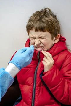Doctor tacking a coronavirus test to an elementary age boy's nose with a medi Foto stock
