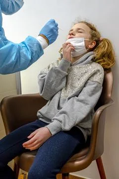 Doctor tacking a coronavirus test to an elementary age girl's nose with a med Stock Photos