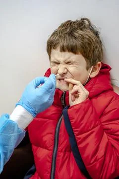 Doctor tacking a coronavirus test to an elementary age boy's nose with a medi Stock Photos