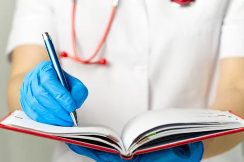 The doctor takes notes in the red diary Stock Photos