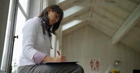 Doctor taking notes on clip board. Vidéo 93864463