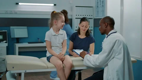 Doctor taking notes on clipboard documents to examine child Stock Footage 169795654