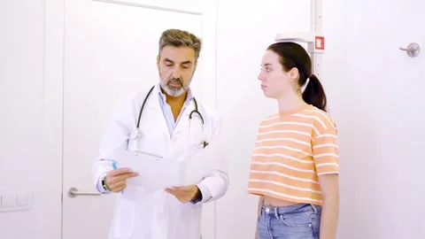 Doctor taking notes in a report while assisting a patient Stock Footage 270397920