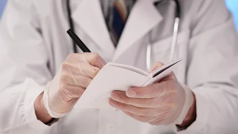 Doctor Taking Notes in a Small Notepad Closeup Stock Footage 128378642