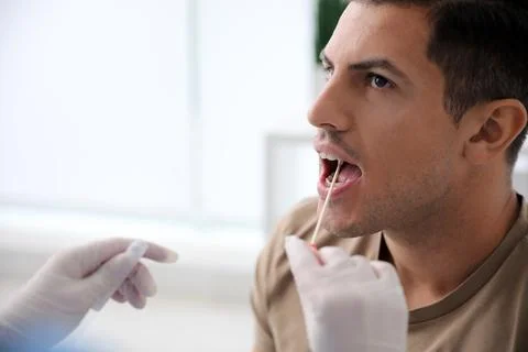 Doctor taking sample for DNA test from man in clinic 스톡 사진