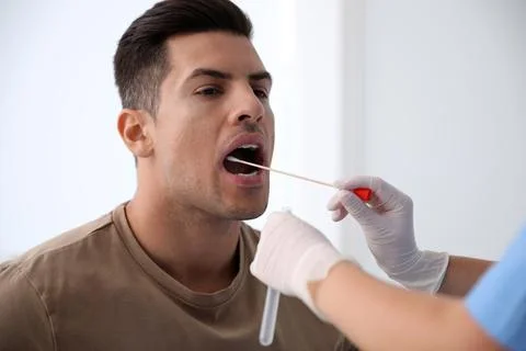 Doctor taking sample for DNA test from man in clinic Stock Photos