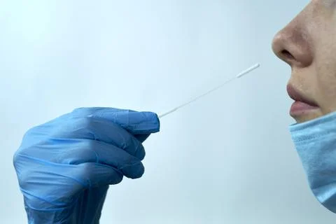 Doctor taking a virus test sample to female patient Stock Photos