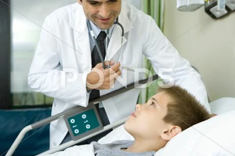 Doctor Talking With Boy Lying In Hospital Bed
