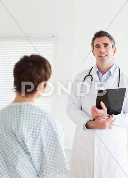 Doctor talking to a charming woman in hospital gown Stock Photos