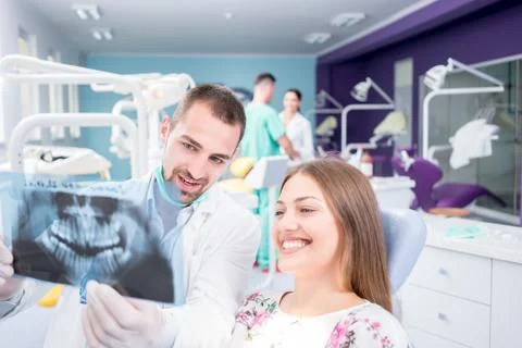 Doctor talking with patient and showing a radiograph in stomatology clinic. D Stock Photos