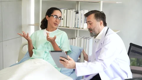 Doctor talking to patient with tablet on bed in hospital Stock Footage 278355617