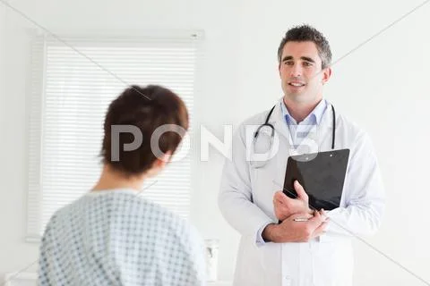 Doctor talking to a woman in hospital gown Stock Photos