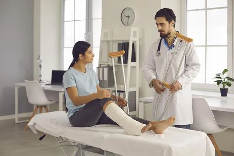 Doctor talks to woman who broke her leg, gives her advice and prescribes Stock Photos