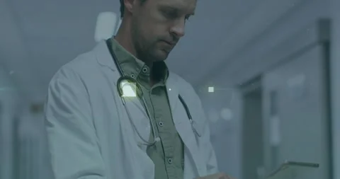 Doctor tapping tablet screen while activating glowing green UI elements and Stock Footage 314790677