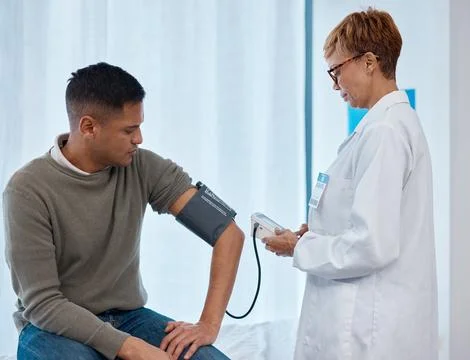 Doctor, test and man with blood pressure in hospital for heart health or Stock Photos