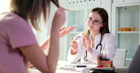 Doctor trichologist offers cure for split ends to female patient in clinic Stock Footage 256292886