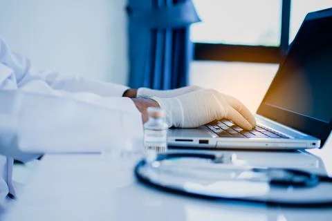 A doctor typing the data and description into a server computer with a lapt.. Stock Photos