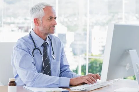 Doctor typing on his computer Stock Photos