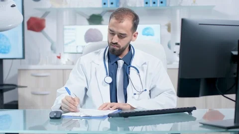 Doctor typing on his computer then he writes in clipboard Stock Footage 108535932