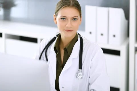 Doctor typing on pc computer while sitting at the desk in hospital office Foto stock