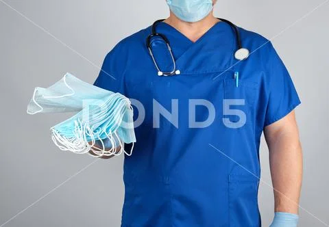 Doctor in uniform and in blue latex gloves keeps sterile masks Stock Photos