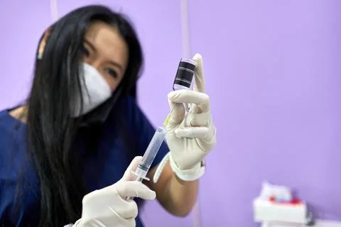 Doctor in uniform talking to mobile while preparing an injection in a clinic Stock Photos