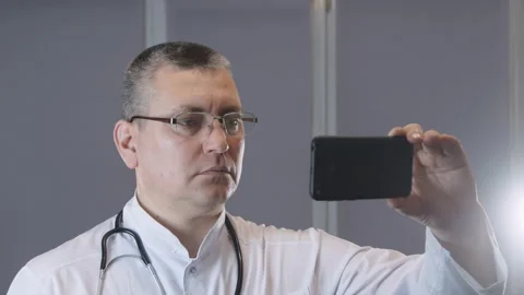 A doctor in uniform talks to a patient in a video chat Stock Footage 123720189