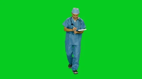Doctor in uniform writing on clipboard while walking on green screen Video stock 124258602