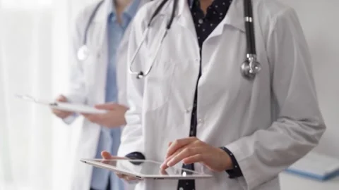 Doctor use a tablet computer for making medication notes while another physician 動画素材 252397070