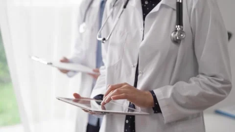 Doctor use a tablet computer for making medication notes while another physician 動画素材 253495553