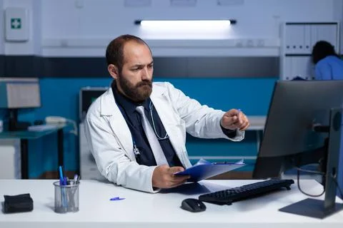 Doctor using computer and checkup files for healthcare work Stock Photos