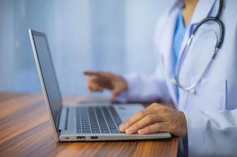 Doctor using computer. Doctor working with laptop computer and writing on p.. Stock Photos