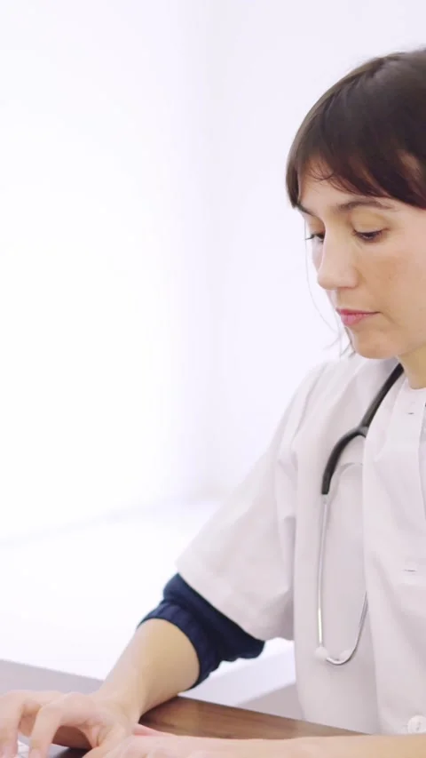Doctor using computer sitting on a desk in a clinic Stock Footage 269772132
