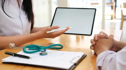 Doctor using computer tablet discussion something with patient. Stock Photos
