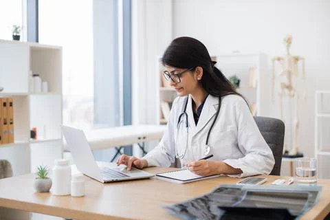 Doctor using computer while sitting at desk in health center Stock Photos