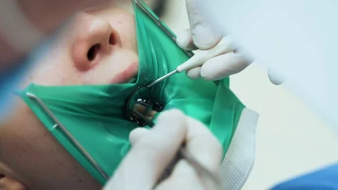 A doctor using dental tools examines a tooth of a young girl. Stock Footage 120184658