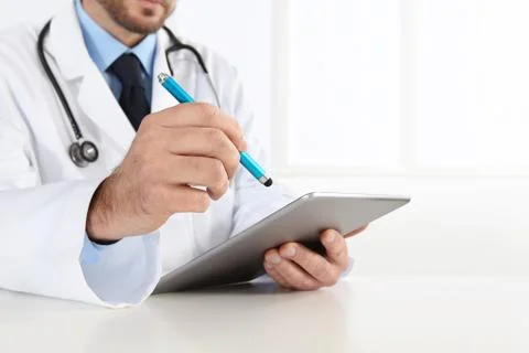 Doctor using digital tablet on desk Stock Photos