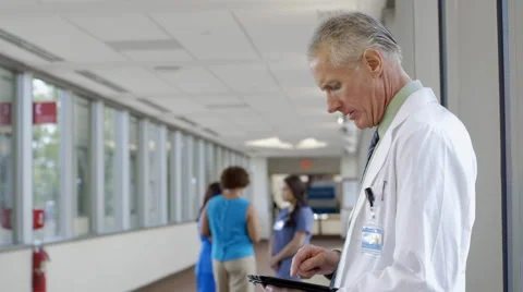 Doctor using digital tablet in hospital corridor Video stock 67178378